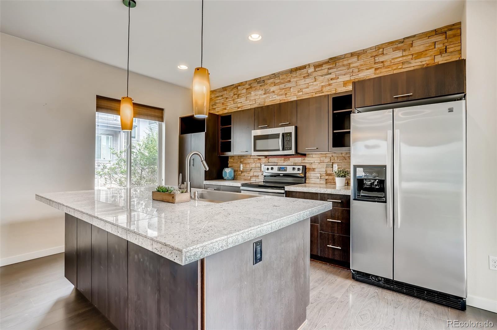9817 Dunning Circle Highlands Ranch, CO 80126 - Photo 9 of 28 a kitchen with kitchen island granite countertop stainless steel appliances cabinets a sink and a center island