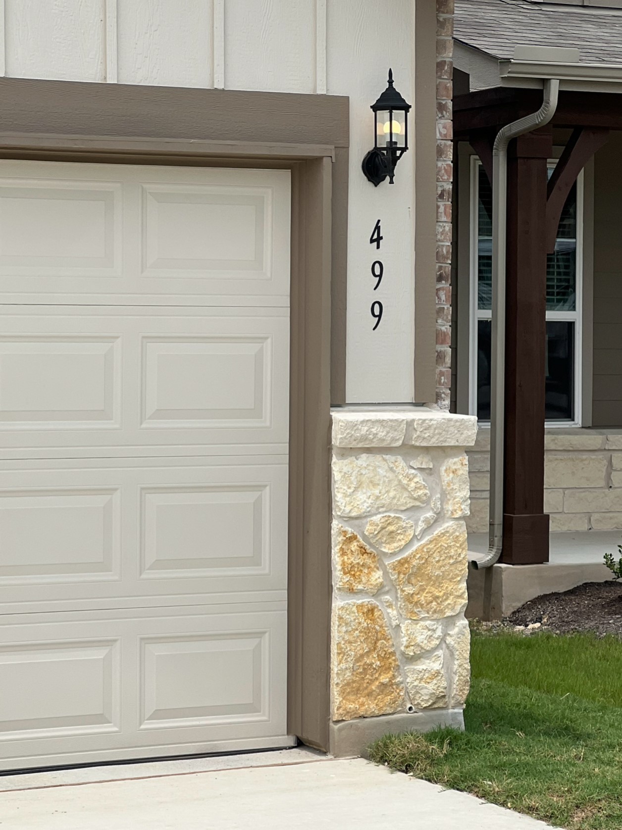 499 Tree Nut Loop Buda, TX 78610 - Photo 2 of 33 A well-appointed garage entrance features stylish stone accents and a classic wall-mounted light fixture.