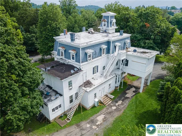 an aerial view of residential house with yard and trees in the background