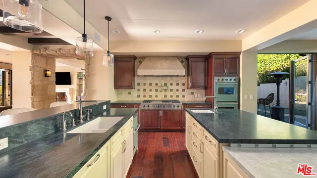 a kitchen with stainless steel appliances granite countertop a sink a stove and a wooden floors