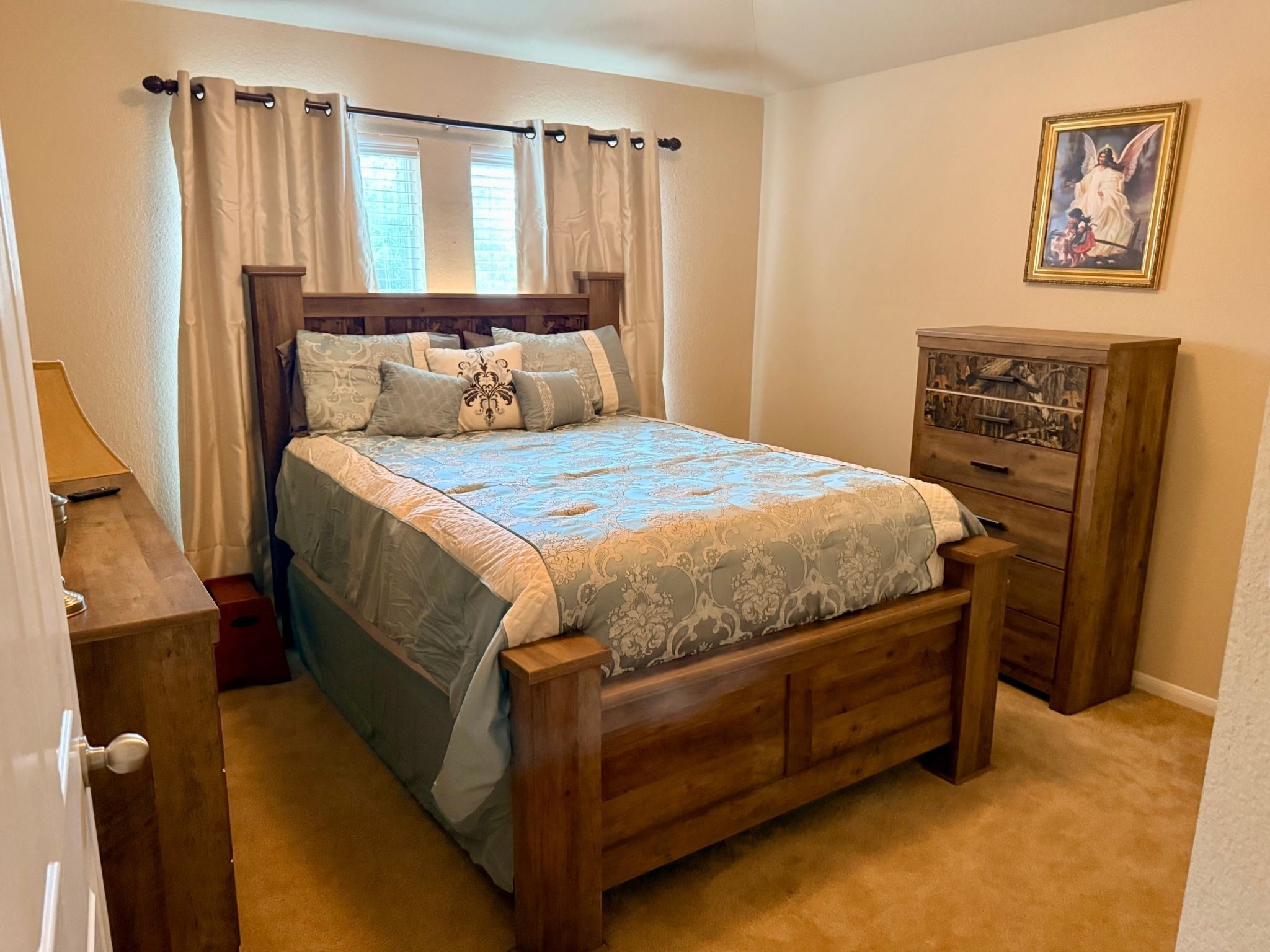 21831 Catoosa Drive Spring, TX 77388 - Photo 11 of 12 Cozy bedroom with warm tones featuring a wooden bed frame and matching furniture. It has carpeted flooring, a window with curtains for natural light, and decorative bedding. The room includes wall art, adding a personal touch.