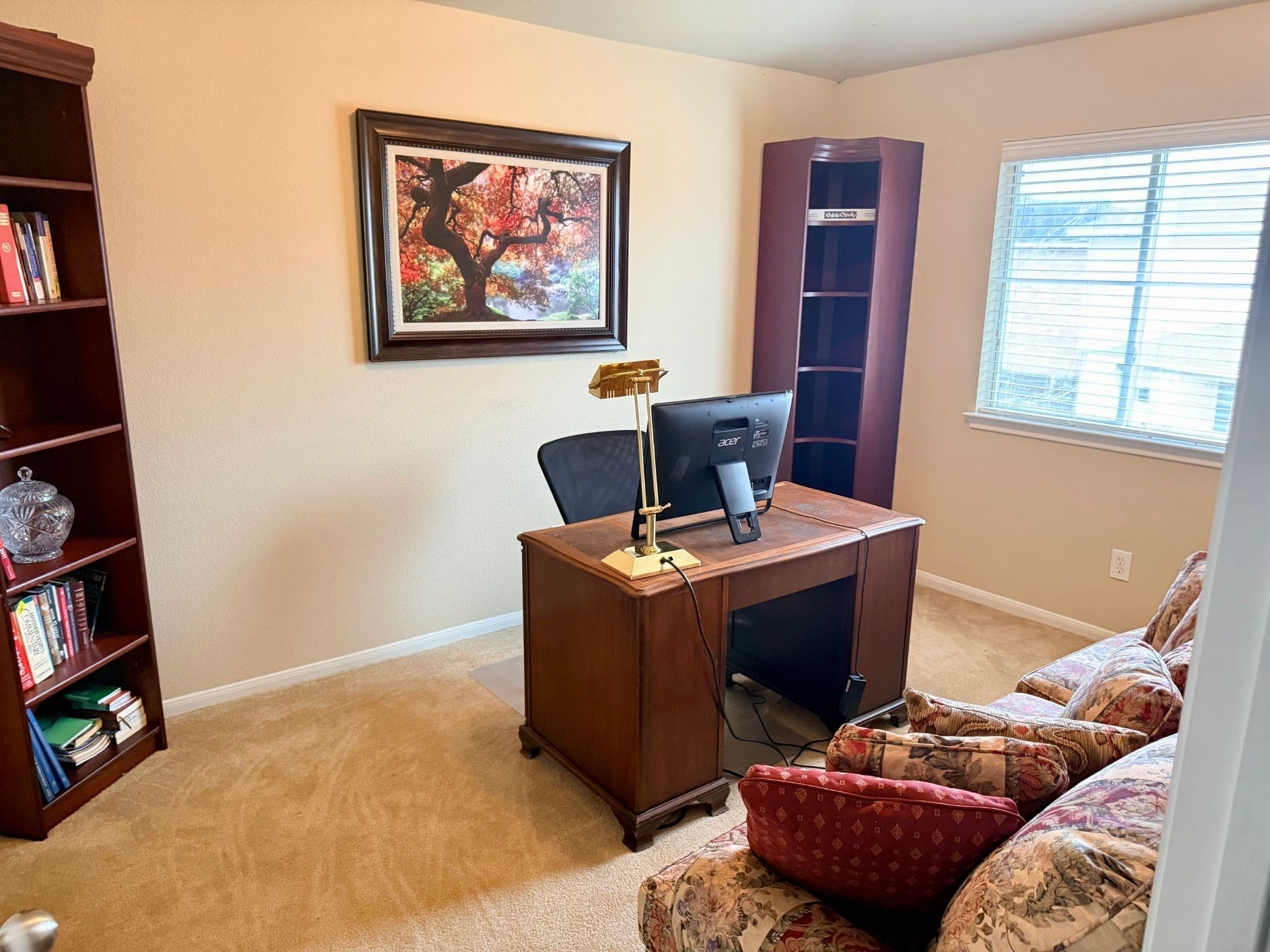21831 Catoosa Drive Spring, TX 77388 - Photo 8 of 12 Cozy home office with warm carpeting and natural light. Features built-in bookshelves, a classic wooden desk, and a comfortable sofa. Ideal for remote work or reading.
