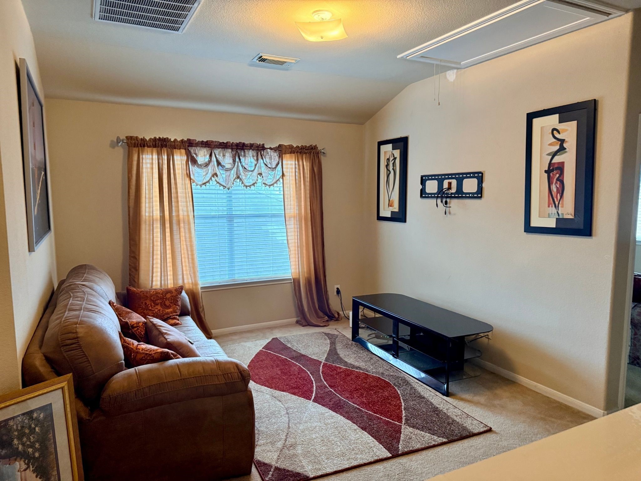 21831 Catoosa Drive Spring, TX 77388 - Photo 10 of 12 Cozy living room with natural light, featuring a comfortable sofa, decorative rug, and wall-mounted TV setup. Framed art adds a touch of elegance, complemented by warm curtains. Perfect for relaxing or entertaining.