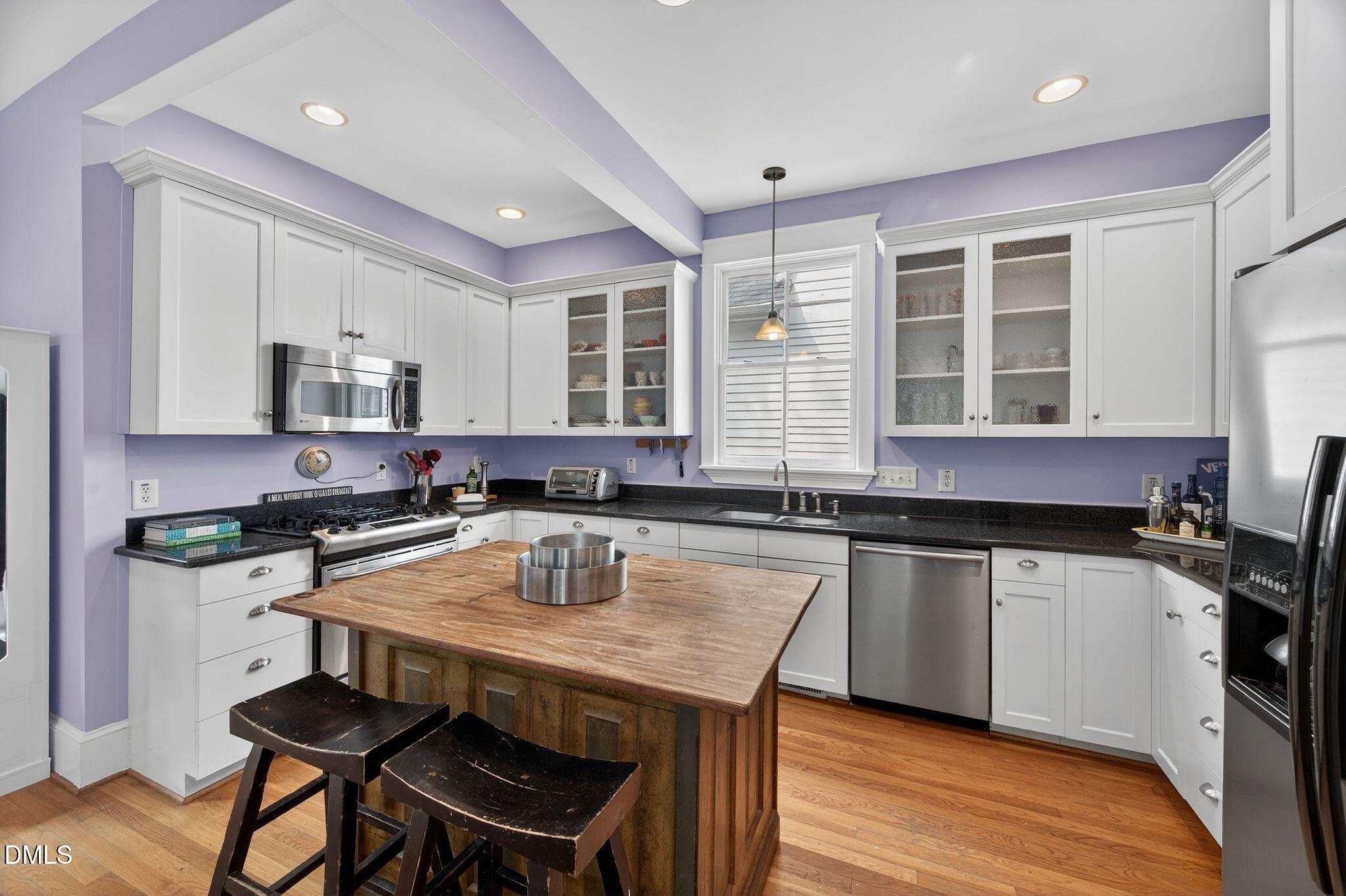 218 Pace Street Raleigh, NC 27604 - Photo 15 of 43 a kitchen with a stove a sink a kitchen island with chairs and wooden floor