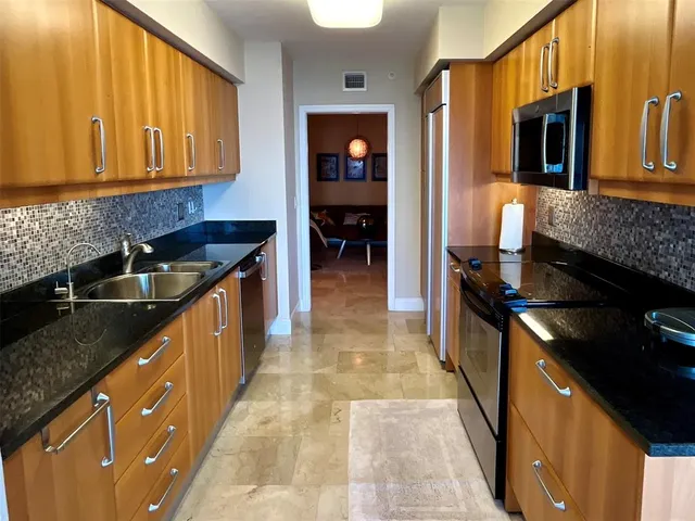 a kitchen with stainless steel appliances granite countertop a stove a sink and a microwave