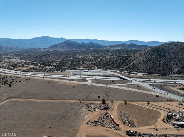 a view of a dry field with mountains in the background