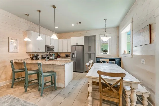 a kitchen with refrigerator a sink and chairs