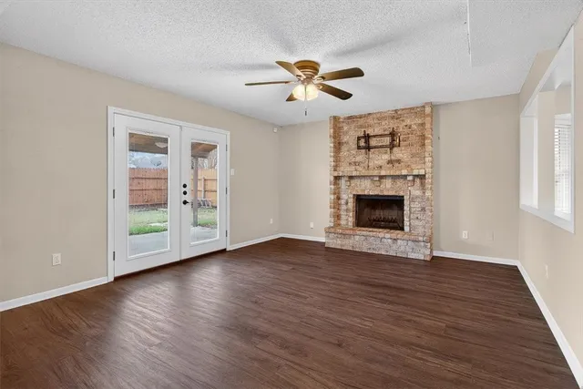 an empty room with wooden floor fireplace and windows