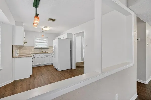 a kitchen with a refrigerator and white cabinets
