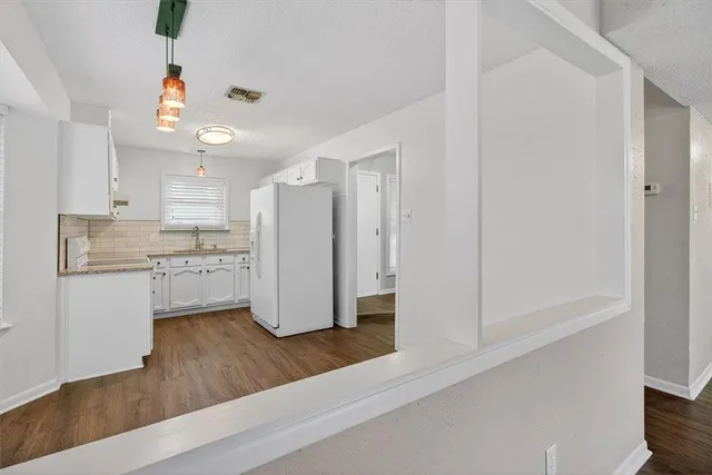 a kitchen with a refrigerator and white cabinets