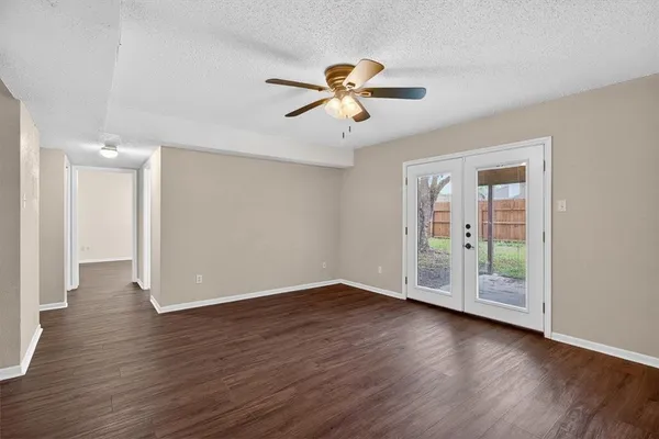 a view of an empty room with window and wooden floor