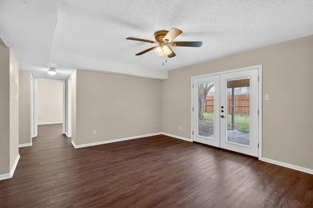 a view of an empty room with window and wooden floor