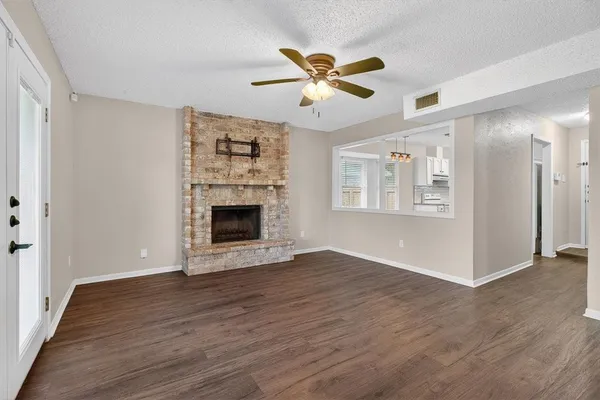 an empty room with wooden floor a ceiling fan and windows