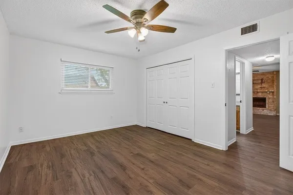 an empty room with wooden floor and ceiling fan