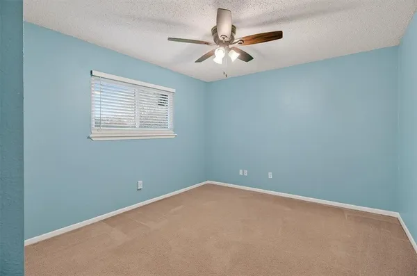 an empty room with a window and a fan