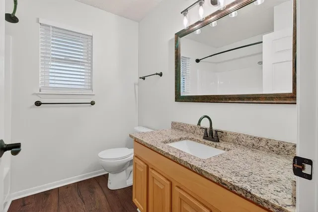 a bathroom with a granite countertop sink toilet and mirror