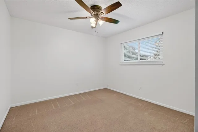 an empty room with a window and a fan