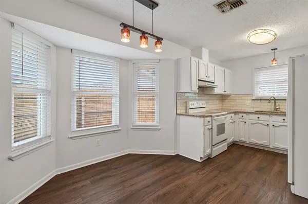 a kitchen with granite countertop white cabinets and white appliances