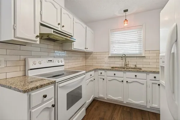 a kitchen with granite countertop white cabinets and white appliances