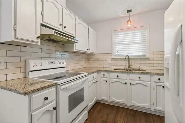 a kitchen with granite countertop white cabinets and white appliances