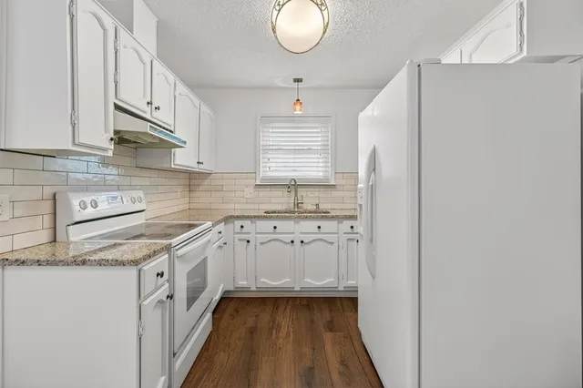 a kitchen with granite countertop white cabinets and white appliances