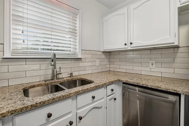 a kitchen with granite countertop white cabinets and a sink