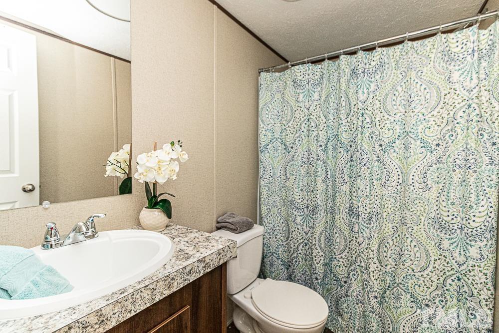 7288 Broad Leaf Dr Spring Spring Hope, NC 27882 - Photo 14 of 19 a bathroom with a granite countertop sink a toilet and a mirror