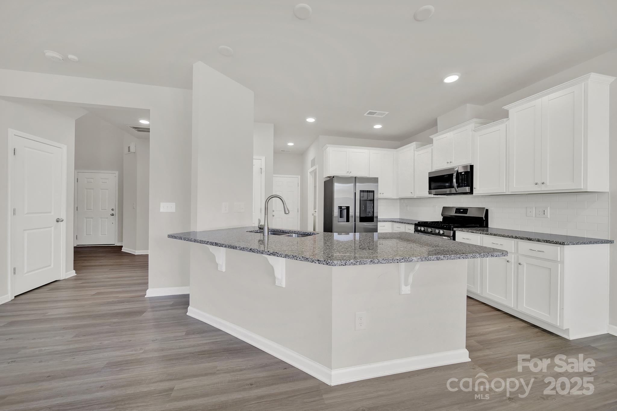 7721 Sea Turtle Way Lancaster, SC 29720 - Photo 13 of 46 a large kitchen with stainless steel appliances granite countertop a stove a sink a refrigerator and white cabinets with wooden floor