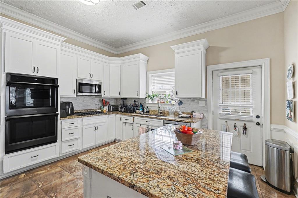 5026 Campbellton Road Southwest Atlanta, GA 30331 - Photo 13 of 39 a kitchen with stainless steel appliances granite countertop a stove top oven a sink dishwasher and a refrigerator with white cabinets
