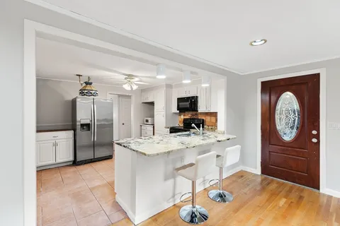 a large kitchen with a refrigerator a stove a sink a dining table and chairs