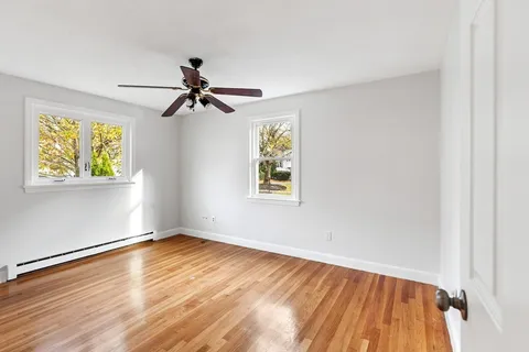 a view of empty room with wooden floor and fan