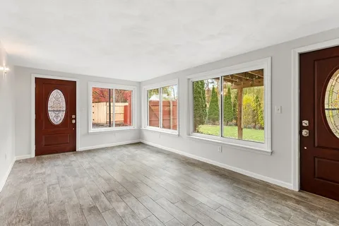 a view of an empty room with a window and wooden floor