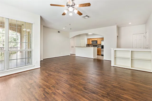 a view of empty room with wooden floor and fan