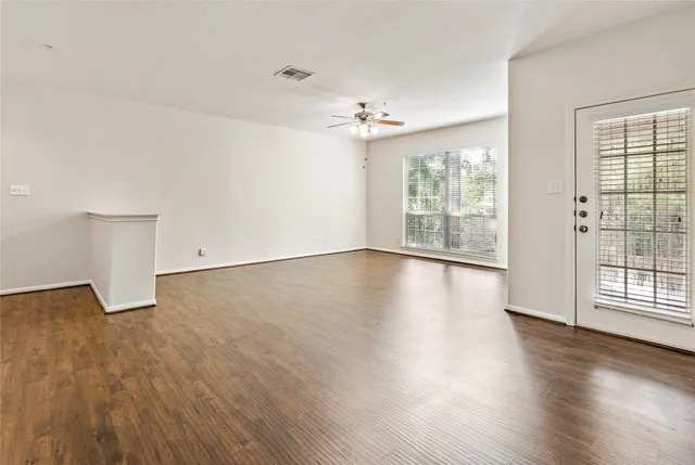 a view of empty room with wooden floor and ceiling fan