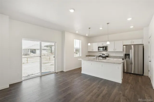 a kitchen with stainless steel appliances kitchen island wooden floors and white cabinets