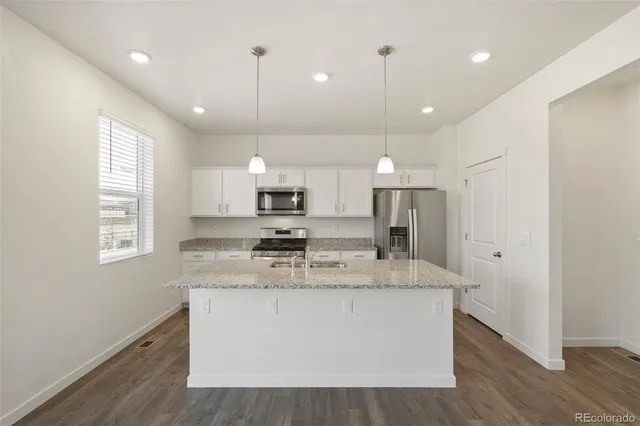 a large kitchen with stainless steel appliances granite countertop a sink a window and wooden floor