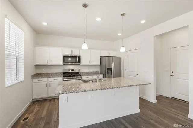 a large kitchen with stainless steel appliances kitchen island a large counter tops and a wooden floor