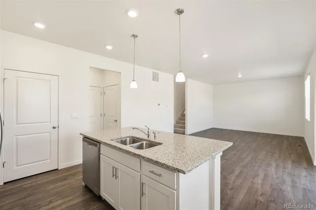 a kitchen with a sink chandelier and wooden floor