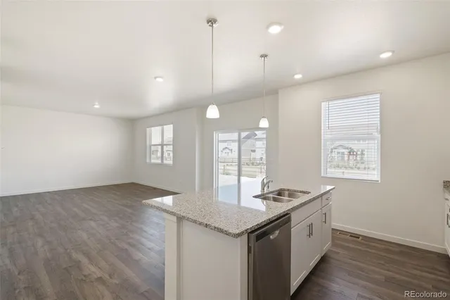 a kitchen with granite countertop a sink cabinets and wooden floor