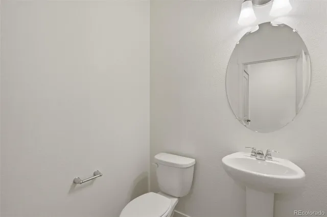 a bathroom with a toilet a sink and mirror