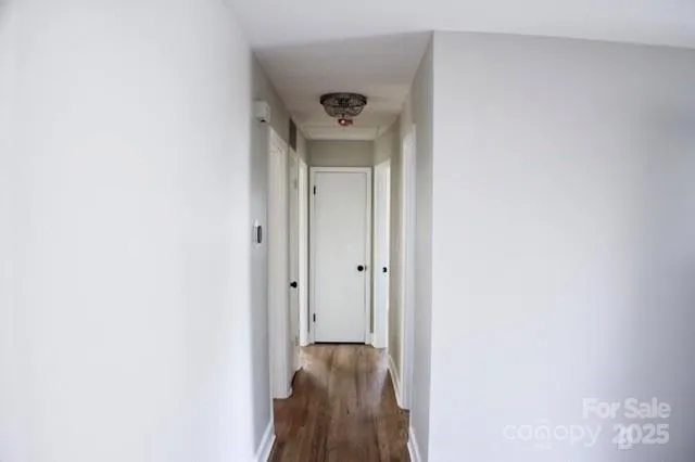 a view of a hallway with a door and a wooden floor