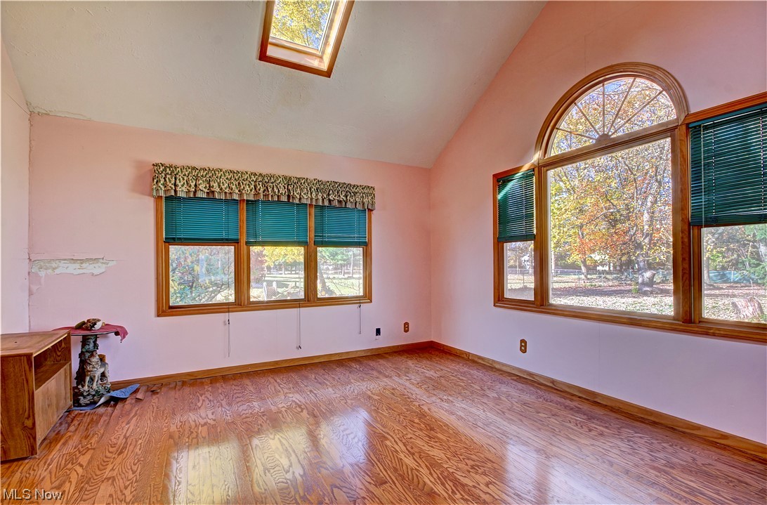20930 Eaton Road Cleveland, OH 44126 - Photo 10 of 33 Empty room featuring a skylight, light wood-type flooring, and high vaulted ceiling