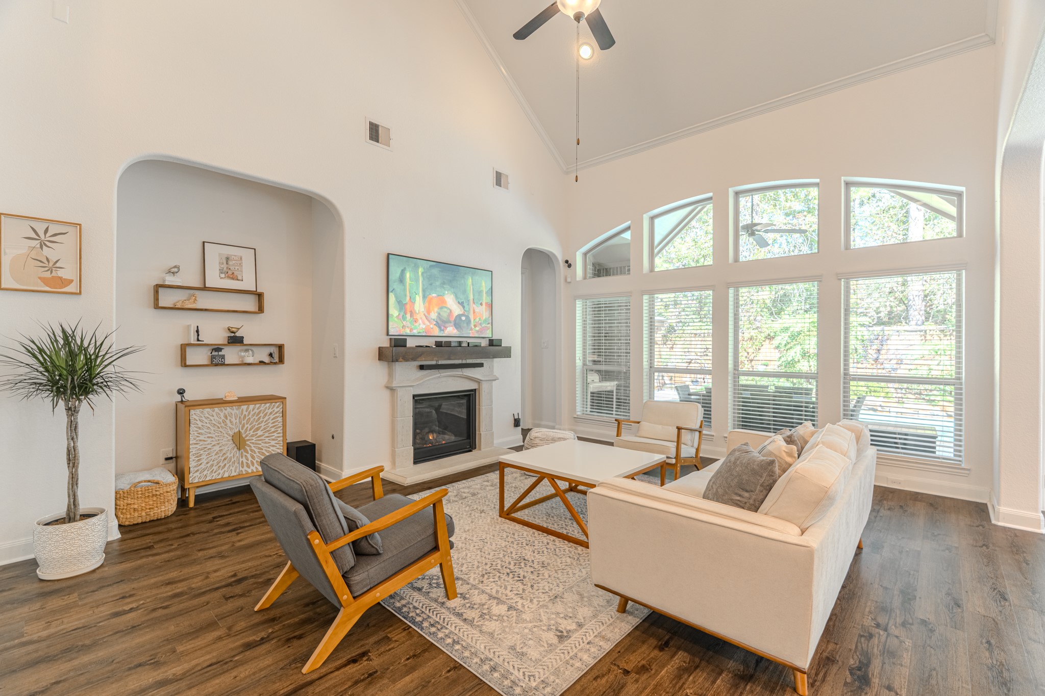 30 Fury Ranch Place The Woodlands, TX 77375 - Photo 20 of 47 This inviting living room features high ceilings, large windows allowing plenty of natural light, a modern fireplace, and stylish wood flooring. The open layout is complemented by contemporary furnishings and tasteful decor, creating a welcoming and airy atmosphere.