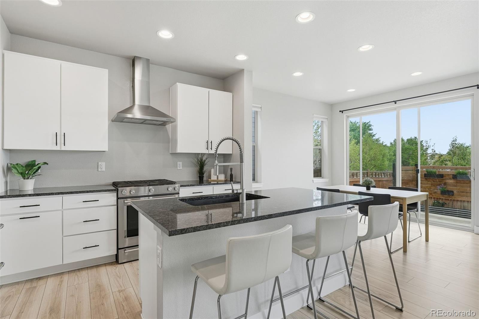2880 West 69th Avenue Denver, CO 80221 - Photo 2 of 45 a kitchen with stainless steel appliances granite countertop a stove a sink and white cabinets with wooden floor