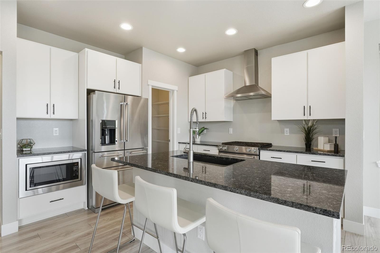 2880 West 69th Avenue Denver, CO 80221 - Photo 5 of 45 a kitchen with stainless steel appliances granite countertop a stove a sink a refrigerator and white cabinets