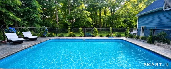 an aerial view of a house with swimming pool and large trees