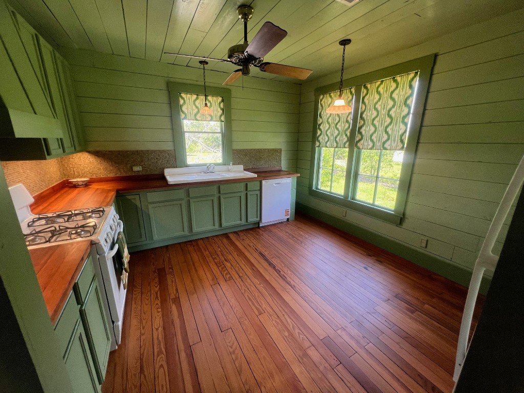 618 Bayridge Road La Porte, TX 77571 - Photo 16 of 50 Discover the charm of this sunlit kitchen featuring a stylish green palette, warm wood floors, and modern convenience with an integrated dishwasher, perfect for culinary adventures.