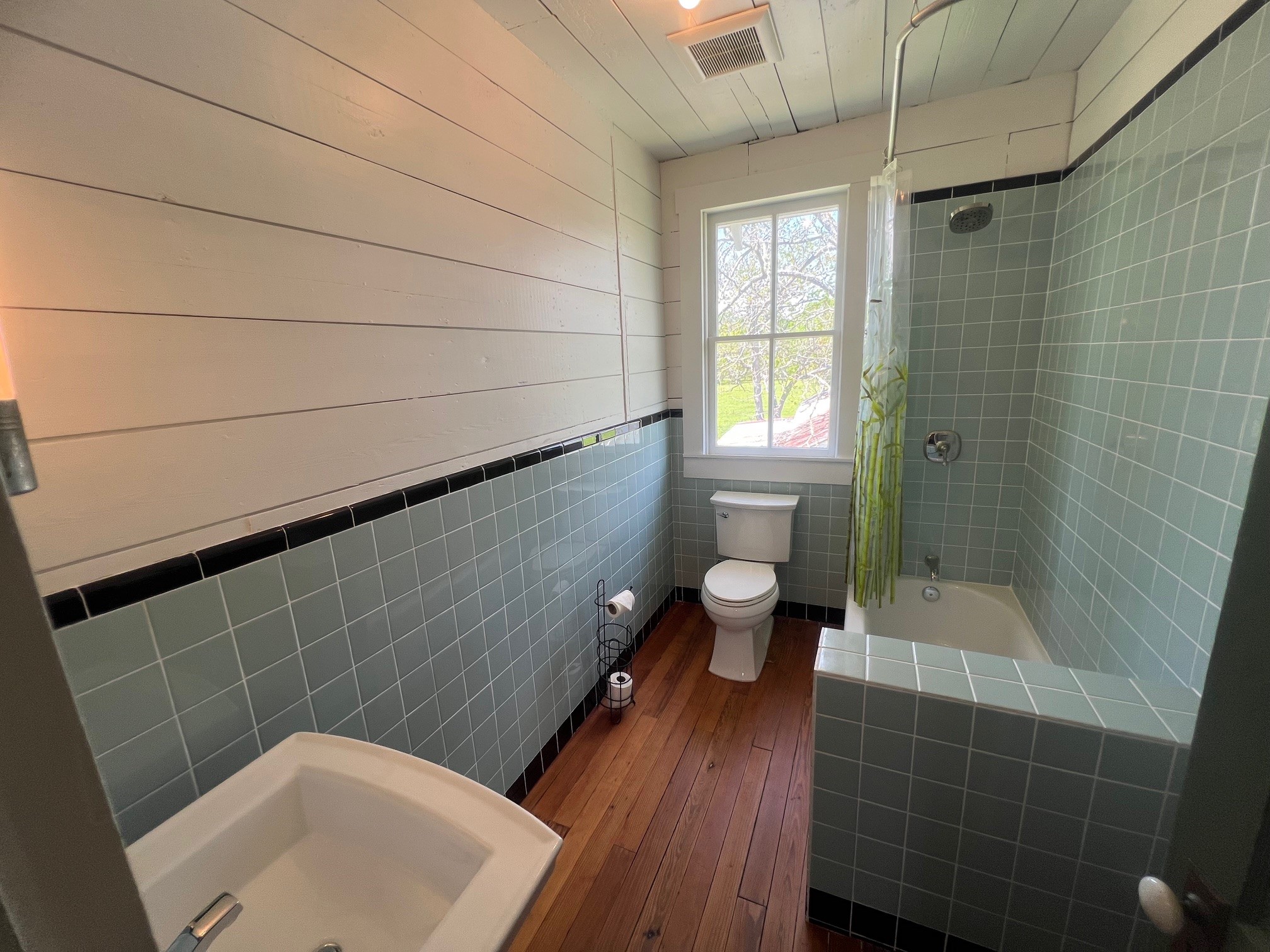 618 Bayridge Road La Porte, TX 77571 - Photo 23 of 50 Experience the perfect blend of rustic charm and modern elegance in this sunlit bathroom, featuring warm wood floors and serene tiled walls.