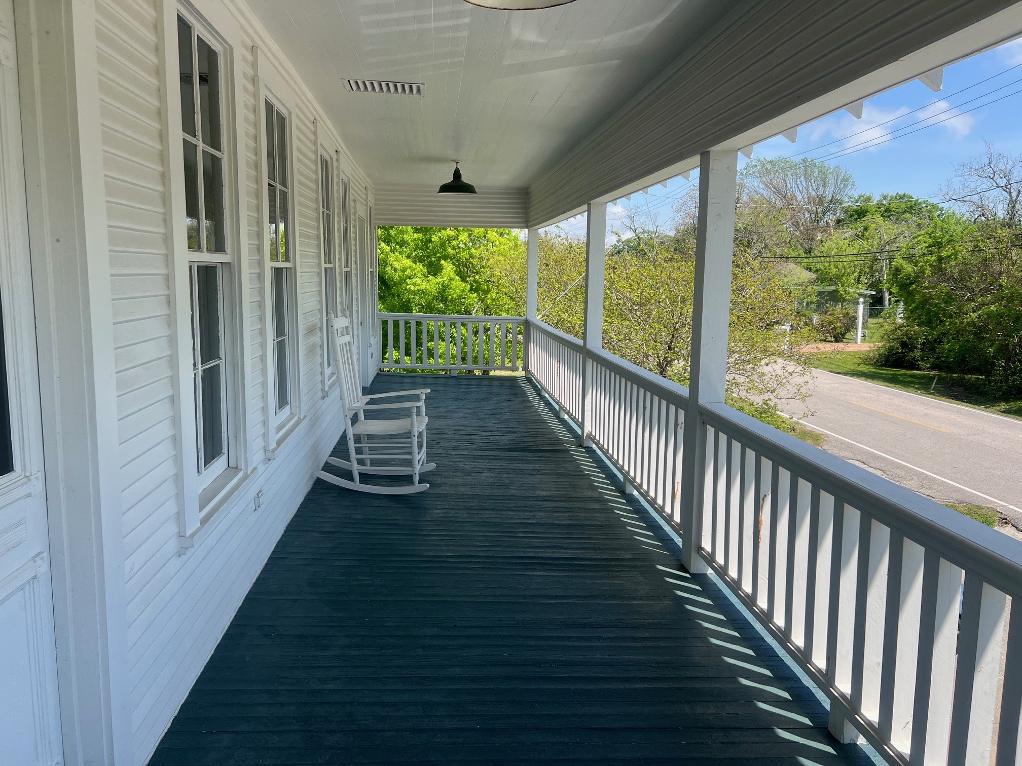 618 Bayridge Road La Porte, TX 77571 - Photo 4 of 50 Experience serene mornings and tranquil evenings on this charming front balcony, perfect for relaxing in a cozy rocking chair while enjoying the lush greenery and quiet street views.