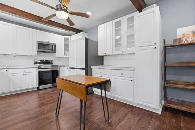 a kitchen with stainless steel appliances granite countertop a refrigerator a stove top oven a sink dishwasher and white cabinets with wooden floor